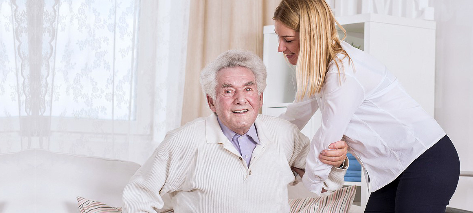 caregiver helping senior man to get up